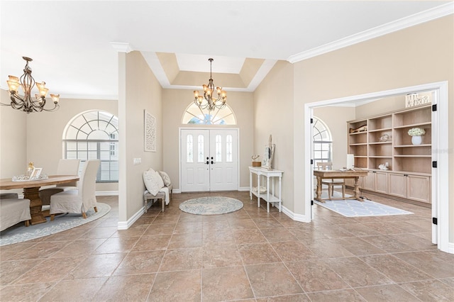 entrance foyer with an inviting chandelier, a tray ceiling, and crown molding