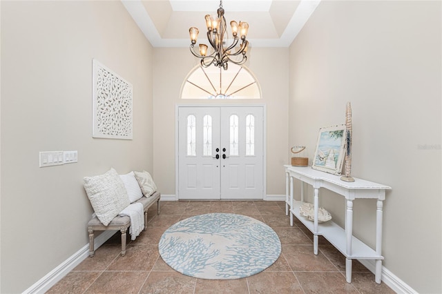 tiled entryway with an inviting chandelier, a tray ceiling, and a high ceiling