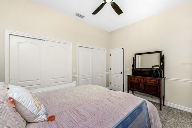 bedroom featuring multiple closets, light carpet, and ceiling fan