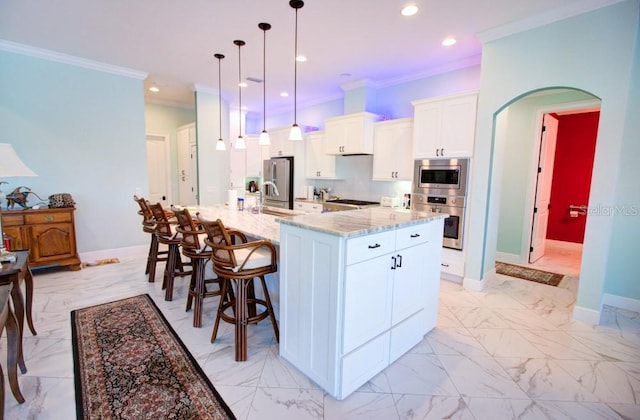 kitchen featuring pendant lighting, appliances with stainless steel finishes, ornamental molding, white cabinets, and a large island with sink