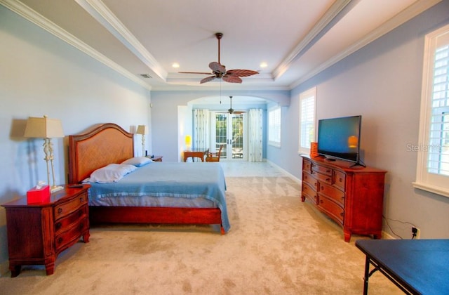 bedroom featuring ceiling fan, ornamental molding, a raised ceiling, and light carpet