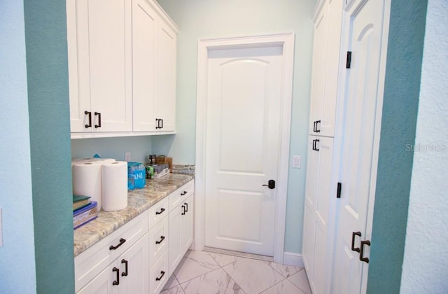 interior space with white cabinetry and light stone counters