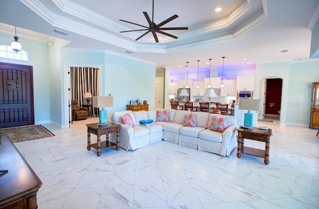 living room featuring a raised ceiling, ornamental molding, and ceiling fan