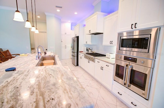 kitchen with pendant lighting, white cabinetry, sink, light stone counters, and stainless steel appliances