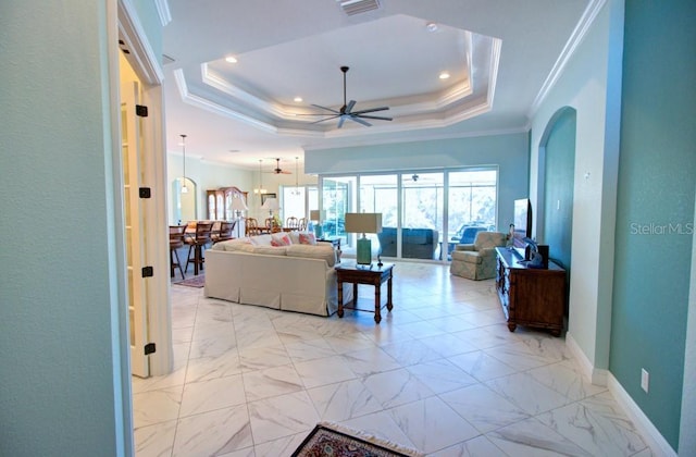 living room featuring crown molding, ceiling fan, and a tray ceiling