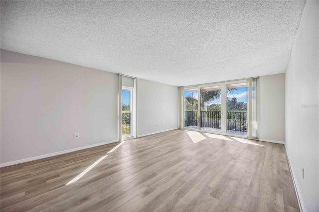 empty room with a healthy amount of sunlight, a textured ceiling, and light wood-type flooring