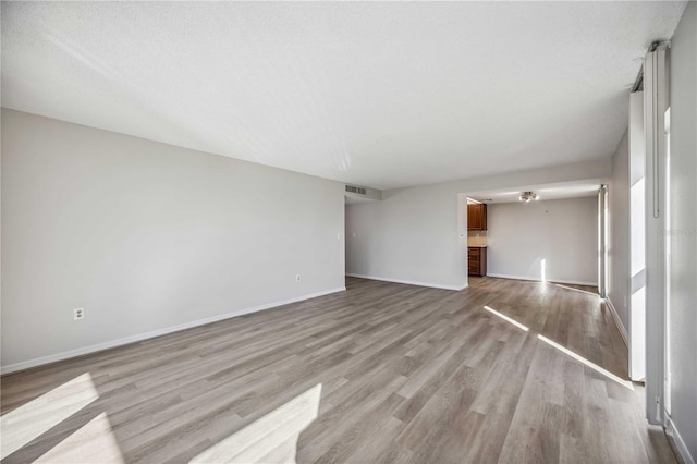 unfurnished room with light hardwood / wood-style flooring and a textured ceiling