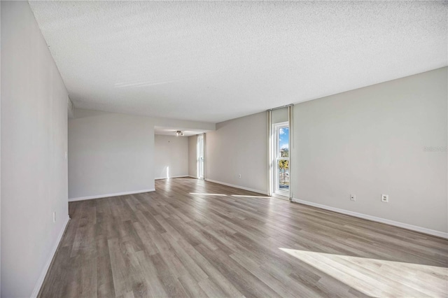 empty room with a textured ceiling and light wood-type flooring