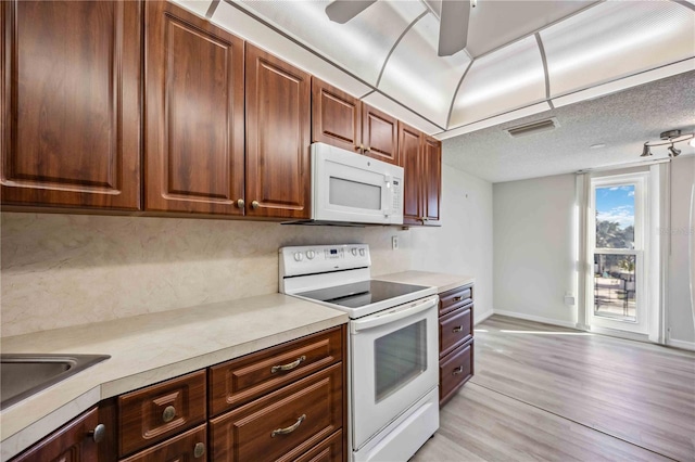 kitchen with white appliances, sink, light hardwood / wood-style floors, and a textured ceiling