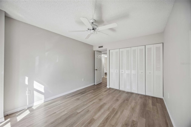 unfurnished bedroom with ceiling fan, a textured ceiling, a closet, and light hardwood / wood-style flooring