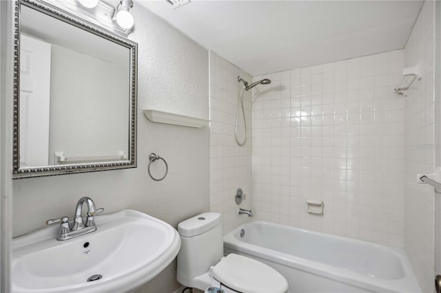 full bathroom featuring tiled shower / bath, toilet, and sink