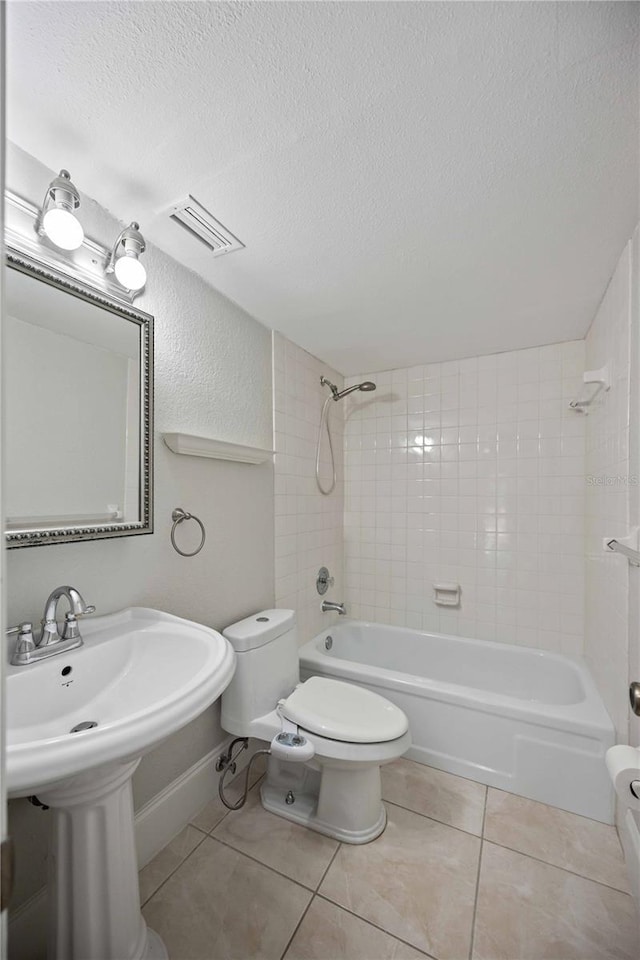 bathroom with tiled shower / bath combo, tile patterned floors, toilet, and a textured ceiling