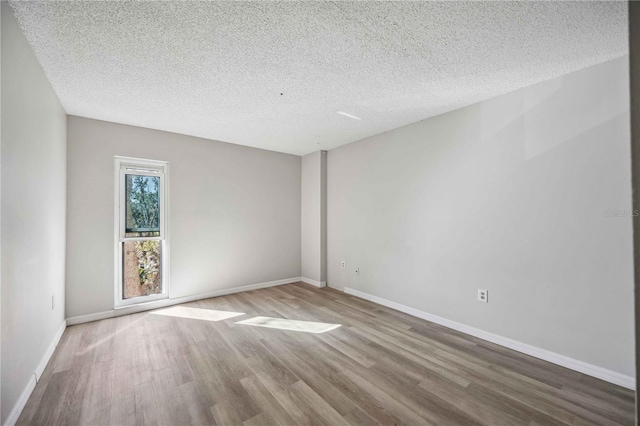 empty room with wood-type flooring and a textured ceiling