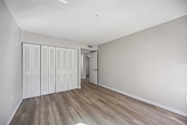 unfurnished bedroom featuring light hardwood / wood-style floors, a closet, and a textured ceiling