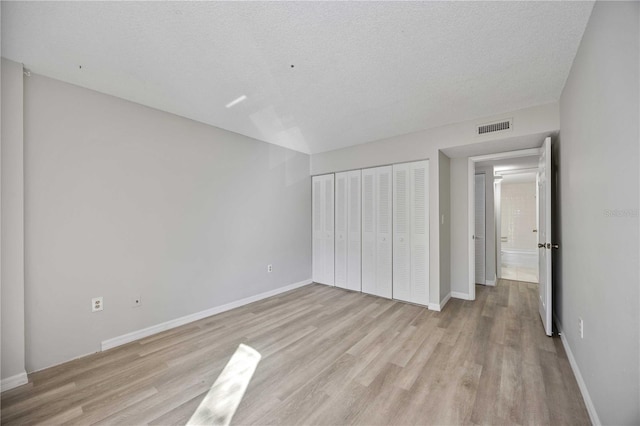 unfurnished bedroom featuring a closet, a textured ceiling, and light wood-type flooring