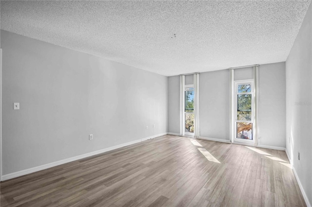 empty room with hardwood / wood-style flooring and a textured ceiling