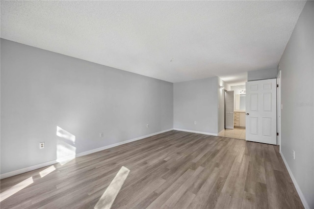 unfurnished room with a textured ceiling and light wood-type flooring