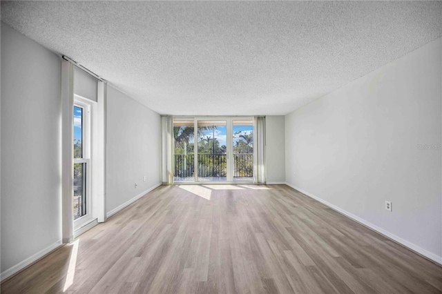 unfurnished room featuring light hardwood / wood-style flooring, a textured ceiling, and a wealth of natural light