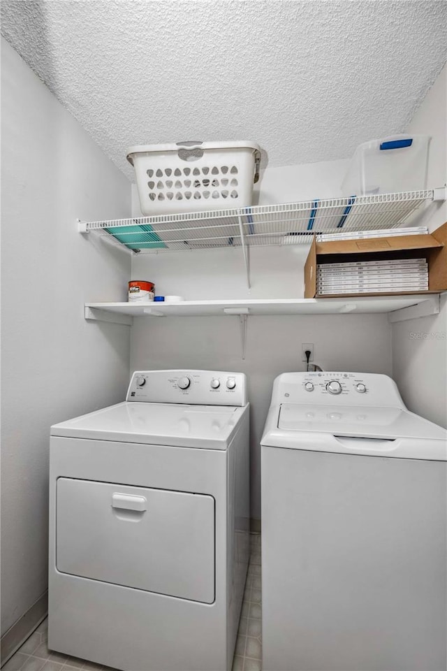 clothes washing area featuring light tile patterned floors, washing machine and dryer, and a textured ceiling