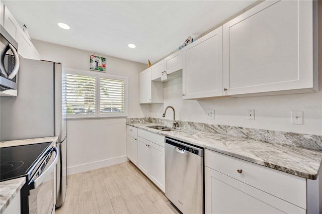 kitchen featuring white cabinetry, appliances with stainless steel finishes, light stone countertops, and sink