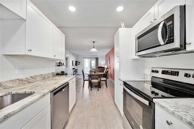 kitchen with white cabinetry, pendant lighting, light hardwood / wood-style floors, and appliances with stainless steel finishes