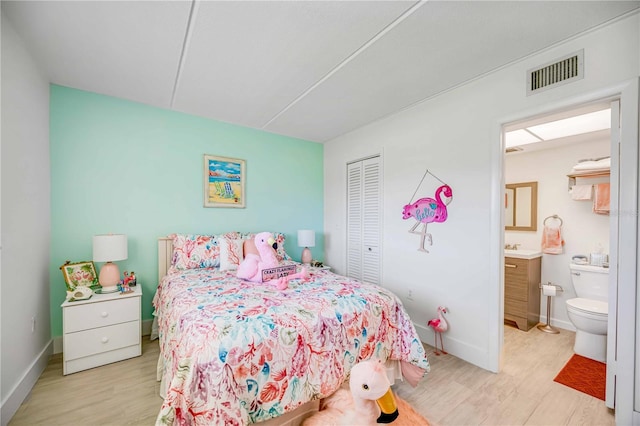 bedroom with ensuite bathroom, a closet, and light wood-type flooring