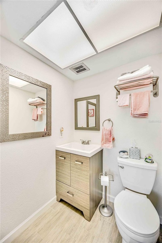 bathroom with vanity, wood-type flooring, and toilet