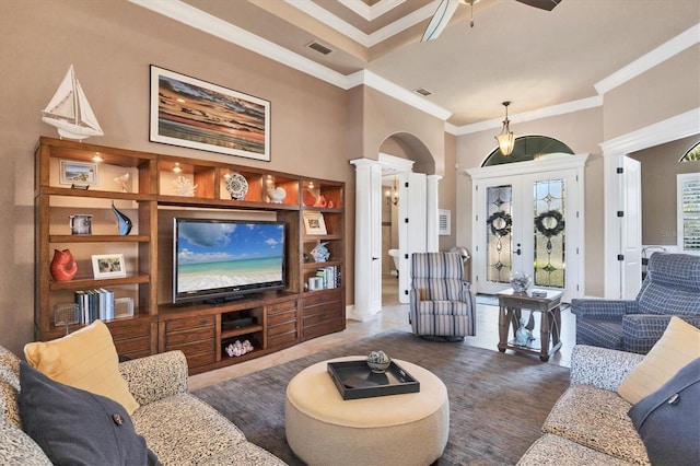 living room with decorative columns, crown molding, a high ceiling, and ceiling fan