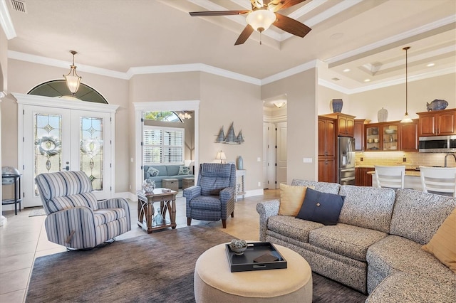 tiled living room featuring french doors, crown molding, ceiling fan, a tray ceiling, and a towering ceiling