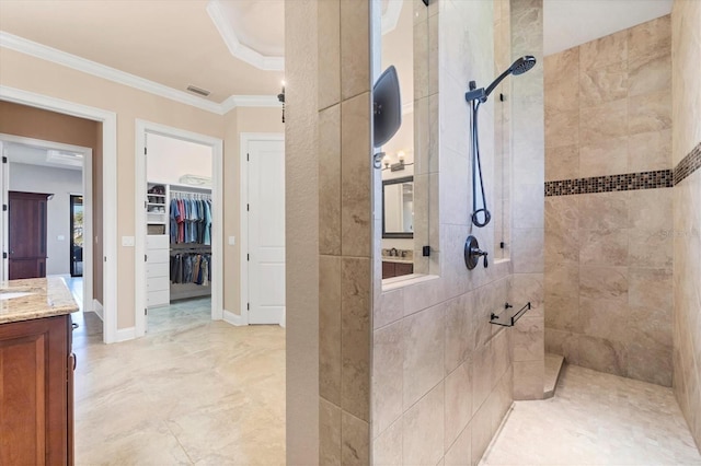 bathroom featuring crown molding, vanity, and a tile shower