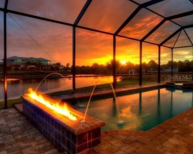 pool at dusk with a lanai, a patio, and pool water feature