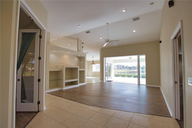 unfurnished living room featuring built in shelves, ceiling fan, high vaulted ceiling, and light tile patterned floors