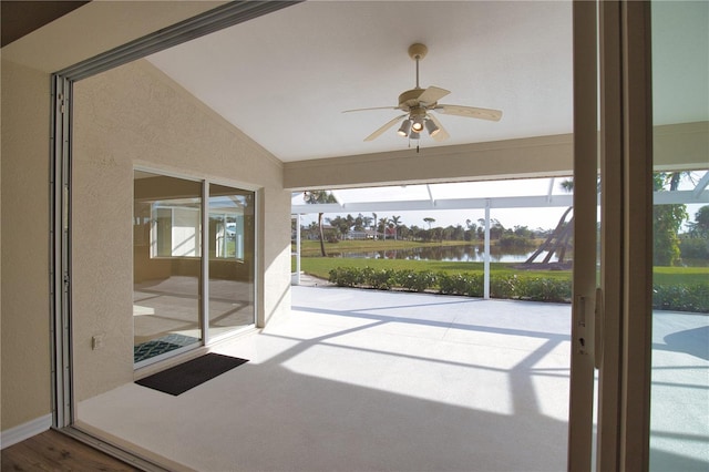 unfurnished sunroom with vaulted ceiling, ceiling fan, and a water view