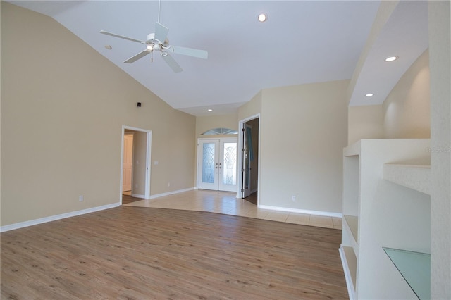 unfurnished living room with high vaulted ceiling, french doors, ceiling fan, and light wood-type flooring