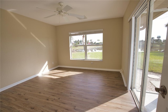 empty room featuring ceiling fan, a water view, and light hardwood / wood-style floors