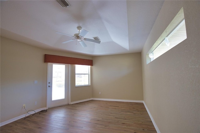 empty room featuring ceiling fan, a tray ceiling, and hardwood / wood-style floors