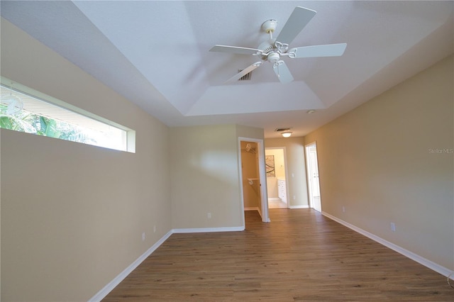 spare room with a raised ceiling, wood-type flooring, and ceiling fan