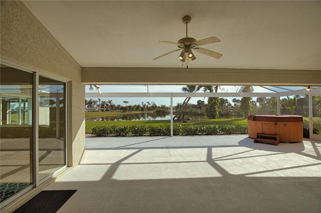 unfurnished sunroom featuring plenty of natural light, ceiling fan, and a water view