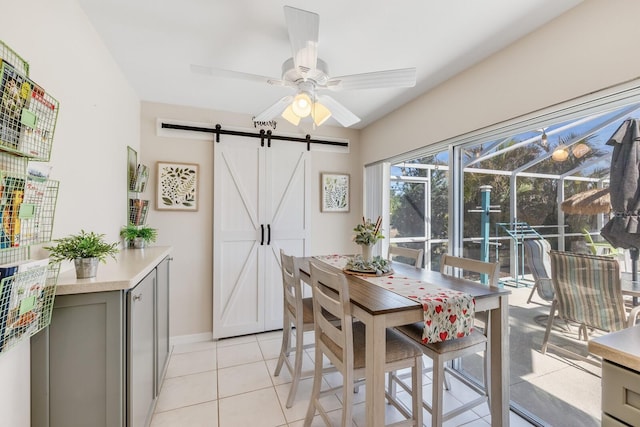 tiled dining space featuring ceiling fan and a barn door