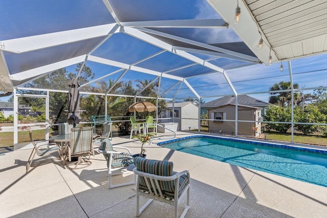 view of swimming pool with a storage shed, a lanai, and a patio area