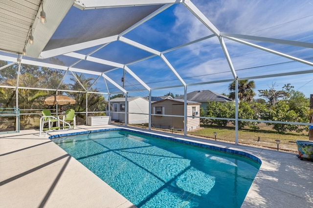 view of pool featuring a patio, glass enclosure, and a shed