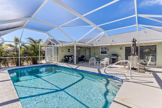 view of swimming pool featuring ceiling fan, area for grilling, glass enclosure, and a patio area