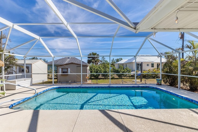 view of swimming pool featuring a patio, glass enclosure, and a storage shed