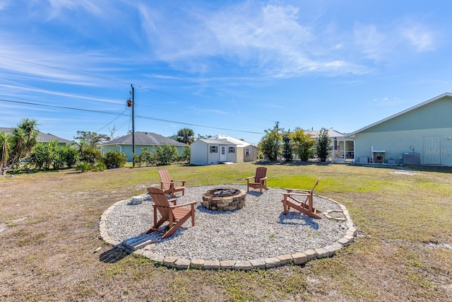 view of yard with a storage unit, central air condition unit, and an outdoor fire pit