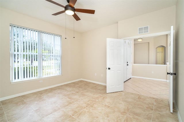 tiled empty room with ceiling fan and lofted ceiling