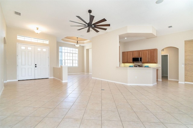 interior space with visible vents, ceiling fan, baseboards, light tile patterned flooring, and arched walkways