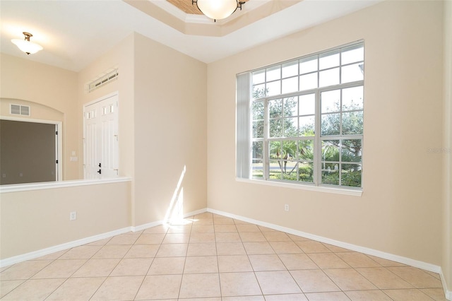 tiled spare room featuring a raised ceiling