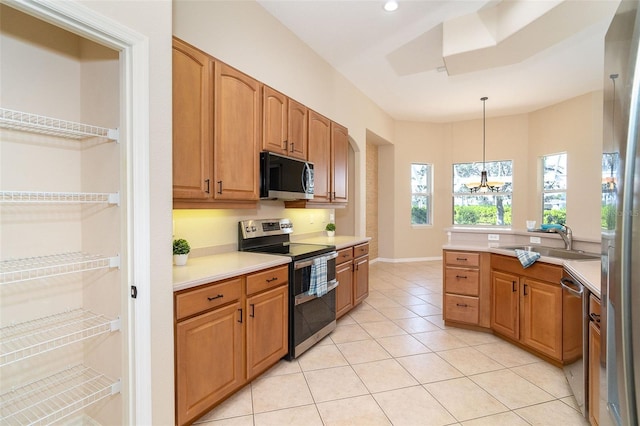 kitchen featuring light tile patterned floors, a sink, light countertops, appliances with stainless steel finishes, and pendant lighting