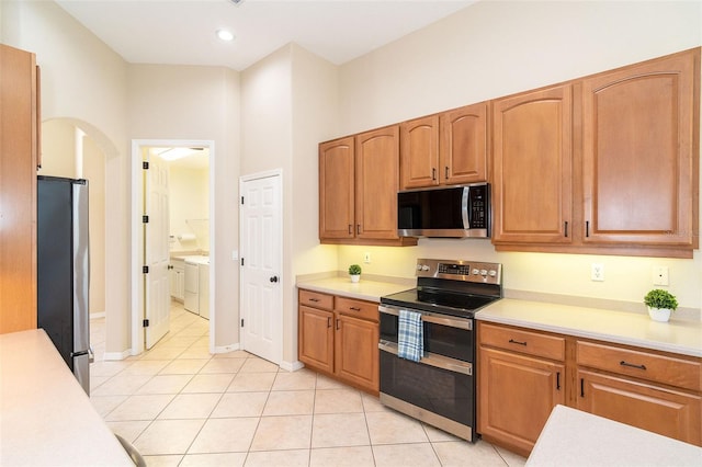 kitchen with light countertops, light tile patterned flooring, arched walkways, and appliances with stainless steel finishes