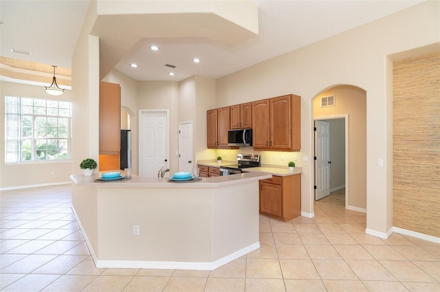 kitchen featuring light tile patterned flooring, arched walkways, visible vents, and stainless steel appliances